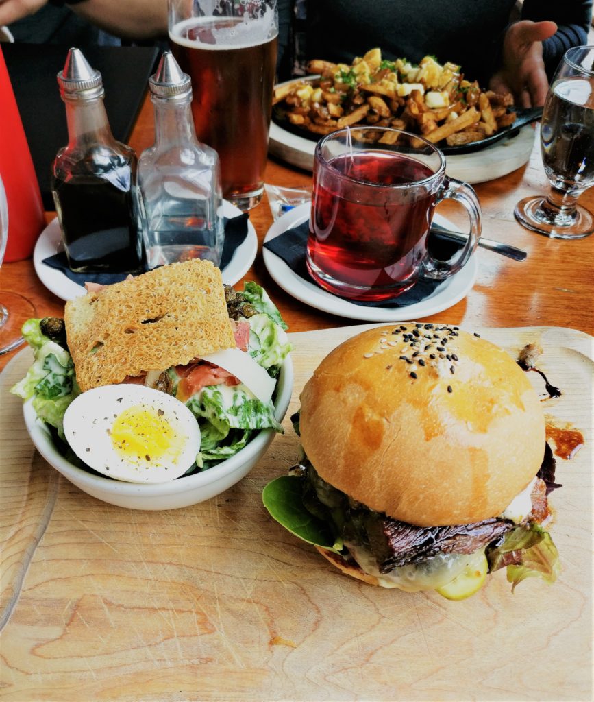 The pony restaurant - The double stack back bacon burger on a wood platter and a Caesar salad garnished with an egg.