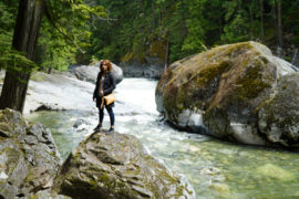 Alicja standing on a boulder in the river off trail in Nairn falls provincial park.