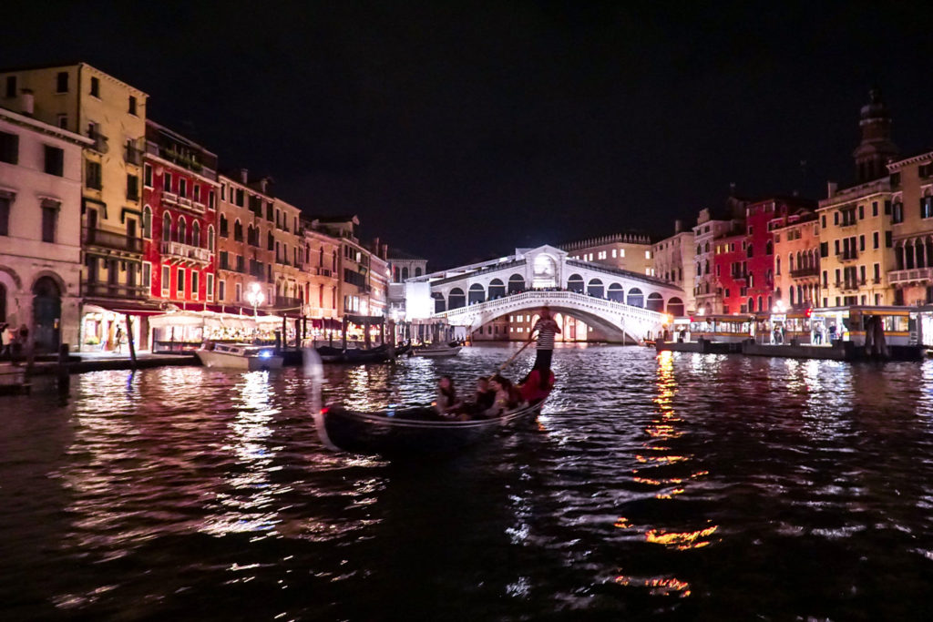 Rialto bridge illuminated at night with a gondola in the foreground. Venice, Italy - Kraska Fox